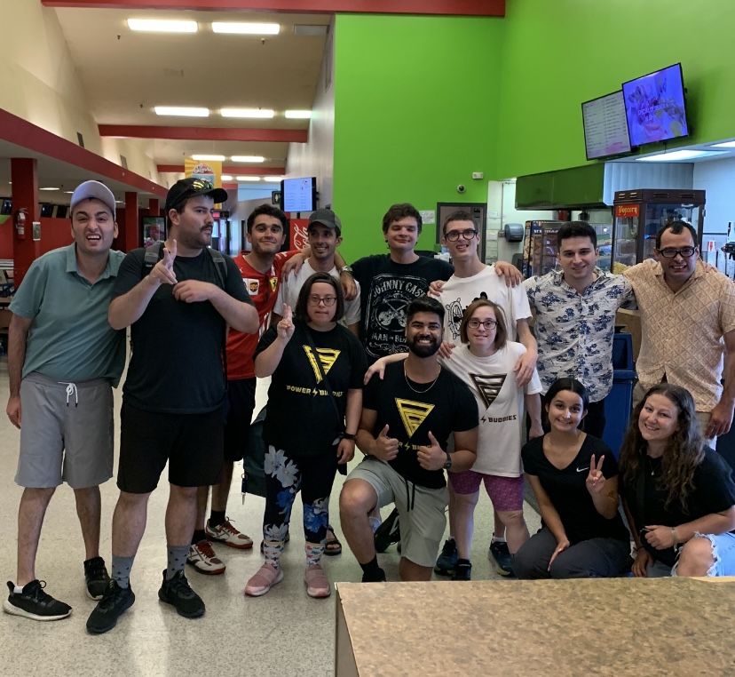 A group of buddies smiling and posing inside a bowling centre