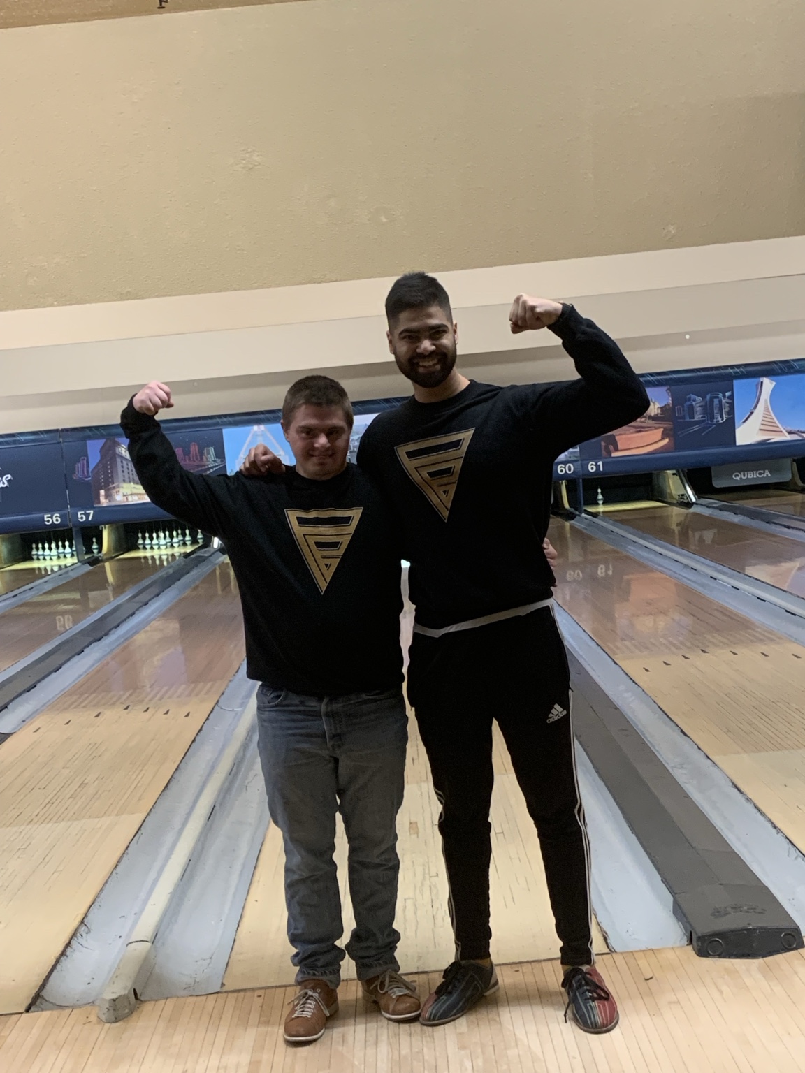 Muhan and a buddy flexing in matching black Power Buddies sweaters at the bowling lanes