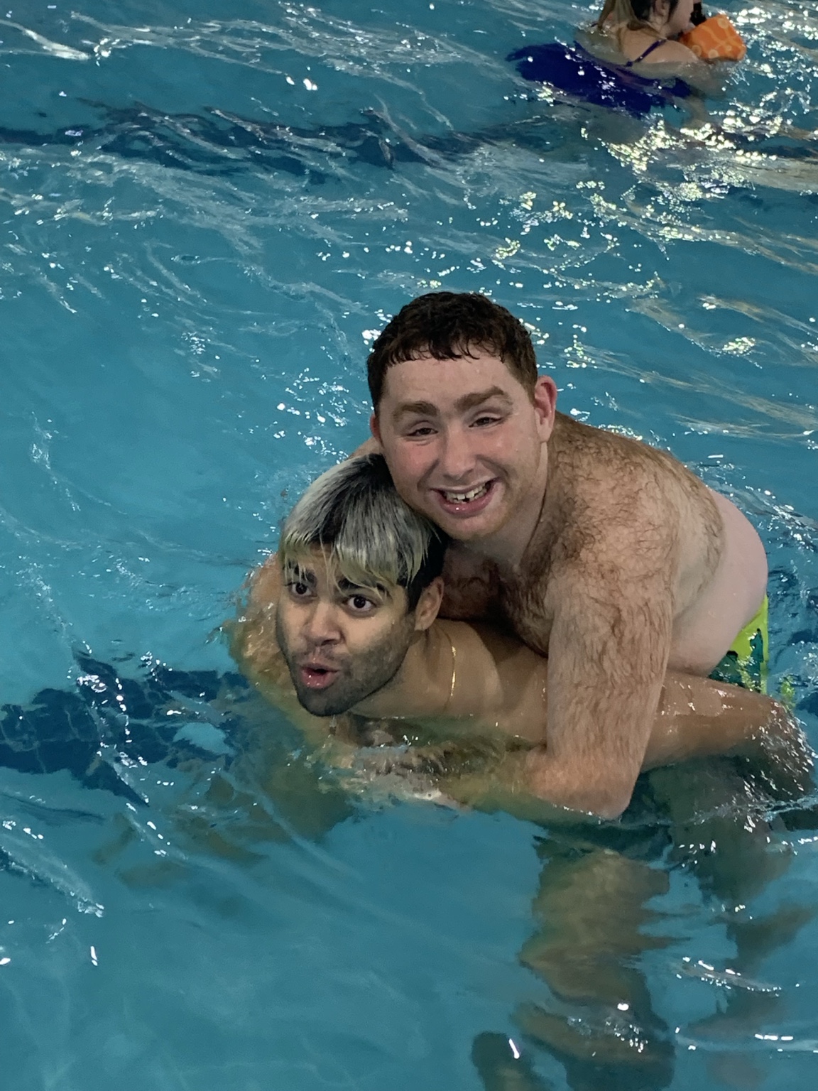 Two buddies smiling together in a swimming pool